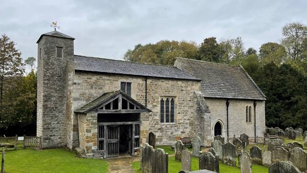 A stone church with a cemetery
Description automatically generated